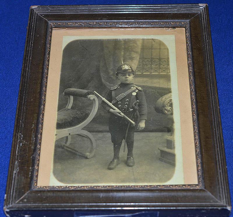 WW1 GERMAN FRAMED PHOTOGRAH OF CHILD WEARING MILITARY UNIFORM WITH SWORD.