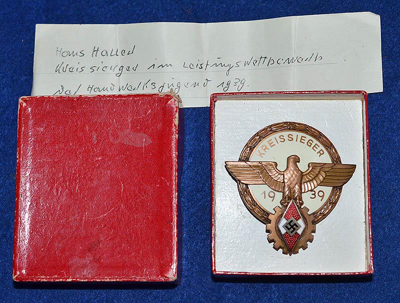 HITLER YOUTH KREISSIEGER 1939 BADGE IN BRONZE WITH RARE ISSUE BOX AND THE ORIGINAL OWNERS PAPER NOTE.