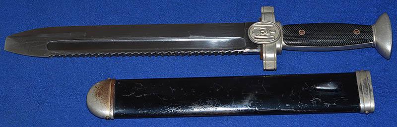 RED CROSS MANS DAGGER WITH MINT SAWBACK BLADE.